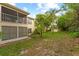 Lawn and natural area behind a two-story condo building with a screened-in balcony and patio at 7910 Hardwick Dr # 717, New Port Richey, FL 34653
