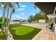 Beautifully landscaped backyard with a putting green, swimming pool, and boat lift on the water at 8848 Sunlit Cove Ne Dr, St Petersburg, FL 33702