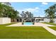 Well-maintained backyard with an outdoor pool, a covered patio, and lush artificial grass at 8848 Sunlit Cove Ne Dr, St Petersburg, FL 33702