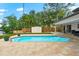 A rectangular in-ground swimming pool with brick pavers and lush landscaping in a private backyard at 8848 Sunlit Cove Ne Dr, St Petersburg, FL 33702