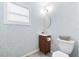 Stylish powder room featuring floral wallpaper, a modern vanity, and a sleek, round mirror at 8848 Sunlit Cove Ne Dr, St Petersburg, FL 33702