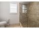 Tiled bathroom featuring glass shower, window, toilet, and neutral-toned flooring at 911 S Sterling Ave, Tampa, FL 33629