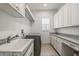 Well-lit laundry room features front loading washer, a utility sink, and ample cabinet space at 911 S Sterling Ave, Tampa, FL 33629
