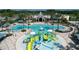 A gorgeous community pool and splash pad with palm trees, sun umbrellas and lounge seating, surrounded by community buildings at 9406 Gladsome Dr, Land O Lakes, FL 34637