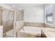 Elegant bathroom featuring a glass-enclosed shower, soaking tub with tile surround, and natural light at 1119 Ballard Green Pl, Brandon, FL 33511
