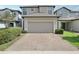 Exterior view of home featuring a large garage door and brick paver driveway, complemented by green landscaping at 1119 Ballard Green Pl, Brandon, FL 33511