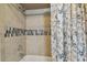 Detailed view of the tiled shower with decorative accent and patterned shower curtain at 12106 Meadow Ln, San Antonio, FL 33576
