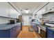 Galley kitchen with blue bottom cabinets, white upper cabinets, stainless steel appliances, and wood-look floors at 12106 Meadow Ln, San Antonio, FL 33576