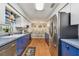 Galley kitchen with stainless steel appliances, blue bottom cabinets, white top cabinets, and wood-look floors at 12106 Meadow Ln, San Antonio, FL 33576