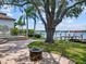 Backyard with a fire pit and a pool is enhanced by mature trees, landscaping, and waterfront access at 150 Carlyle Dr, Palm Harbor, FL 34683