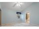 This light blue bedroom features a ceiling fan, window with valance, and doorway to the bathroom at 150 Carlyle Dr, Palm Harbor, FL 34683