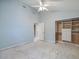 Spacious light blue bedroom featuring a ceiling fan, closet with drawers, and doorway to the bathroom at 150 Carlyle Dr, Palm Harbor, FL 34683