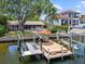 Waterfront home with a private dock, boat lifts, and outdoor seating area at 150 Carlyle Dr, Palm Harbor, FL 34683