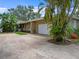 Spacious driveway leading to a two-car garage, surrounded by lush, tropical landscaping at 150 Carlyle Dr, Palm Harbor, FL 34683