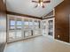 Bright sunroom with tiled floor, ceiling fan, and lake view through white shuttered windows at 150 Carlyle Dr, Palm Harbor, FL 34683