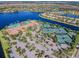 Amazing community aerial featuring a swimming pool, tennis courts, mature landscaping, and sparkling lake at 16101 Cape Coral Dr, Wimauma, FL 33598