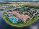 Stunning aerial view of resort-style community amenities with pools, clubhouse, tennis courts, and picturesque landscaping near the water at 16101 Cape Coral Dr, Wimauma, FL 33598