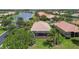 Beautiful aerial view of the tan-roofed home with screened-in lanai overlooking lush landscaping and the lake at 16101 Cape Coral Dr, Wimauma, FL 33598