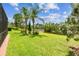 Large backyard with well-maintained lawn, mature palm trees, and scenic pond views at 16101 Cape Coral Dr, Wimauma, FL 33598