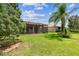 Expansive backyard featuring a screened-in patio with a ceiling fan and lush green lawn at 16101 Cape Coral Dr, Wimauma, FL 33598