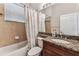 Bathroom features a granite countertop, wood cabinet, a bathtub with shower, and tiled accents at 16101 Cape Coral Dr, Wimauma, FL 33598