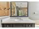 Close up on a grey vanity with granite countertops and large mirror showing shower and bathroom at 16101 Cape Coral Dr, Wimauma, FL 33598
