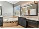 Bright bathroom featuring a tub with tile surround, granite countertop vanity, and large framed mirror at 16101 Cape Coral Dr, Wimauma, FL 33598