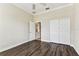 Bedroom with wood floors, double door closet, ceiling fan, and view into the foyer creates a comfortable private space at 16101 Cape Coral Dr, Wimauma, FL 33598