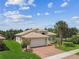 Well-manicured home with tile roof, red brick driveway, and lush tropical landscaping at 16101 Cape Coral Dr, Wimauma, FL 33598