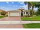 Inviting single Gathering home featuring a brick driveway, attached garage, and beautifully landscaped front yard at 16101 Cape Coral Dr, Wimauma, FL 33598