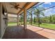 Screened-in patio featuring brick flooring, ceiling fan, view to the grassy backyard, pond, and mature trees at 16101 Cape Coral Dr, Wimauma, FL 33598