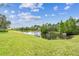Scenic backyard featuring a pond with beautiful trees and a lush green lawn at 16101 Cape Coral Dr, Wimauma, FL 33598