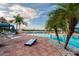 Inviting pool area with palm trees, lounge chairs and paver deck with view of the lake at 16101 Cape Coral Dr, Wimauma, FL 33598
