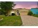 Charming single-story home featuring a paved driveway, a well-manicured lawn, and mature landscaping at 1758 Biarritz Cir, Tarpon Springs, FL 34689