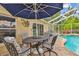 Charming in-ground pool with brick pavers, shaded seating, and a screened enclosure at 1758 Biarritz Cir, Tarpon Springs, FL 34689
