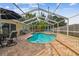 A kidney shaped in-ground pool is surrounded by brick pavers and a screened enclosure at 1758 Biarritz Cir, Tarpon Springs, FL 34689
