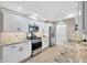 Kitchen features white cabinets, stainless steel appliances, and stone countertops at 1890 Wateroak W Dr, Clearwater, FL 33764