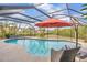 Stunning screened-in pool featuring a waterfall feature, patio seating, and lush landscaping at 1890 Wateroak W Dr, Clearwater, FL 33764