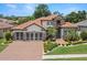 Stunning two-story home with a terracotta roof, lush landscaping, and brick driveway at 2142 Scarlet Oaks St, Clearwater, FL 33759
