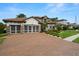 Elegant home featuring a brick driveway, three-car garage, and well-manicured landscaping at 2142 Scarlet Oaks St, Clearwater, FL 33759