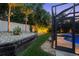 Lush landscaping and decorative rock bordering the screened pool area and home exterior at 2142 Scarlet Oaks St, Clearwater, FL 33759