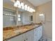 Bathroom featuring granite countertops, double sinks, large mirror with decorative lighting, and glass enclosed shower at 23739 Forest View Dr, Land O Lakes, FL 34639
