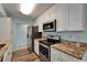 Modern kitchen featuring stainless steel appliances, granite countertops, white cabinetry and wood-look flooring at 23739 Forest View Dr, Land O Lakes, FL 34639