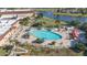Aerial view of community pool showcasing ample seating, shaded tables, and lush landscaping by a serene lake at 2413 Oxford Down Ct # 58, Sun City Center, FL 33573