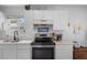 Well-lit kitchen features white cabinets, a stainless steel range, and a window with a pleasant view at 2413 Oxford Down Ct # 58, Sun City Center, FL 33573
