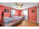 Bedroom features coral walls, wood floors, two windows, and an overhead fan at 3621 Beacon Square Dr, Holiday, FL 34691