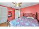 Bedroom features coral walls, wood floors, a closet, and an overhead fan at 3621 Beacon Square Dr, Holiday, FL 34691