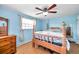 A bright bedroom with blue walls, wood floors, a wood frame bed, and a ceiling fan at 3621 Beacon Square Dr, Holiday, FL 34691