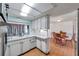 Well lit kitchen with white cabinets, light green brick accent wall, and view into dining room at 3621 Beacon Square Dr, Holiday, FL 34691