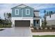 Charming two-story home with a gray garage door, blue siding, and a well-manicured lawn at 37114 Sagemoor Dr, Zephyrhills, FL 33541
